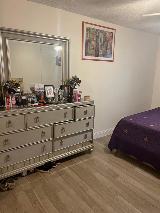 bedroom with a textured ceiling and light hardwood / wood-style flooring