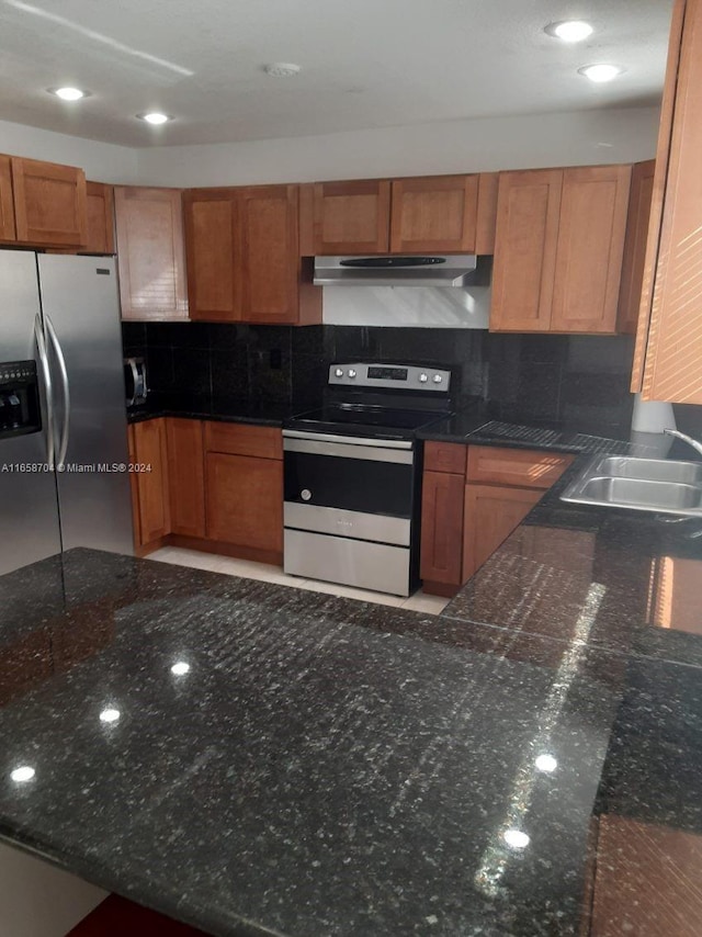 kitchen featuring appliances with stainless steel finishes, dark stone counters, tasteful backsplash, and sink