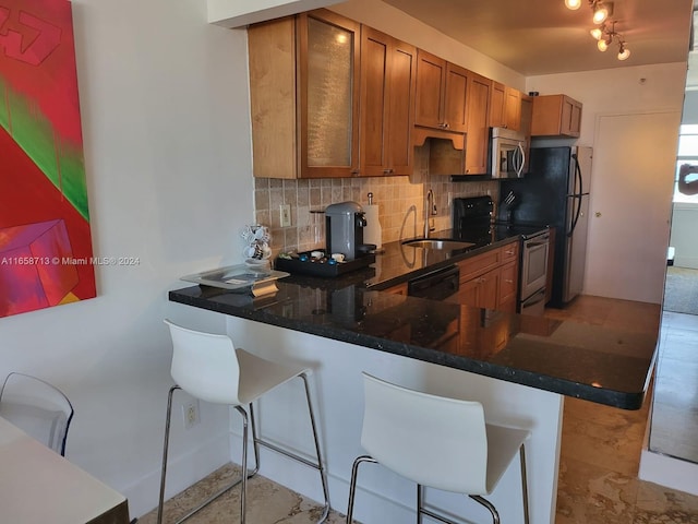 kitchen featuring tasteful backsplash, kitchen peninsula, stainless steel appliances, a kitchen bar, and sink