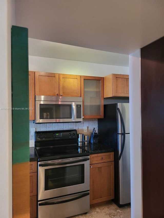 kitchen featuring dark stone counters, backsplash, and stainless steel appliances