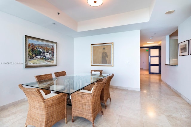 dining area featuring light tile patterned floors and a tray ceiling