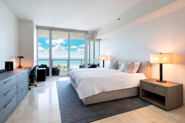 bedroom featuring access to outside, a water view, and a wall of windows