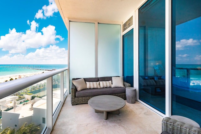 balcony featuring an outdoor living space, a view of the beach, and a water view