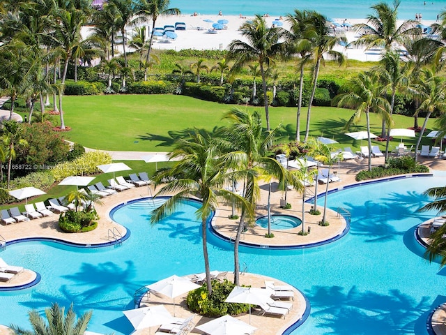 view of swimming pool with a community hot tub and a yard