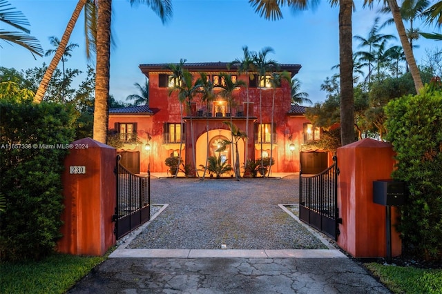 view of front facade featuring a fenced front yard, driveway, a balcony, and a gate