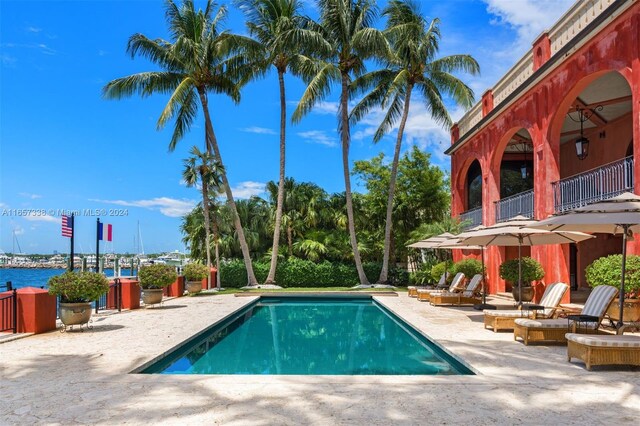 view of pool featuring a water view, a fire pit, and a patio