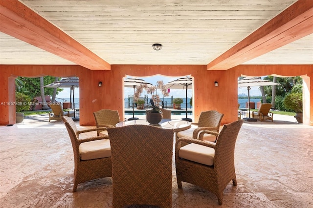 dining area featuring plenty of natural light, beamed ceiling, and wooden walls