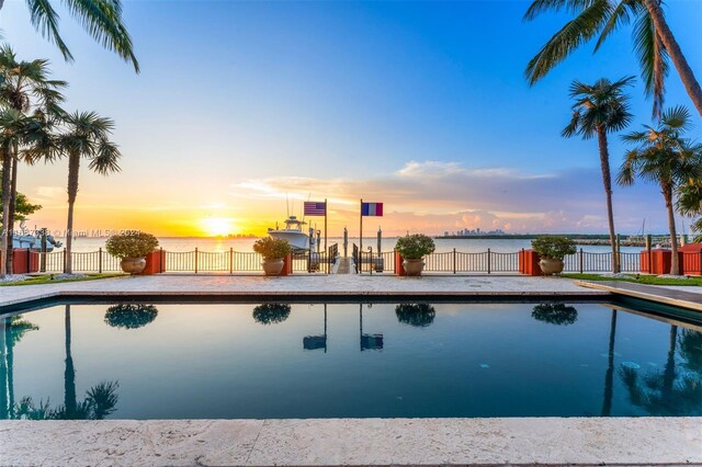 pool at dusk featuring a water view