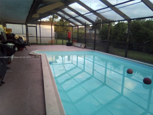 view of swimming pool featuring glass enclosure and a patio area