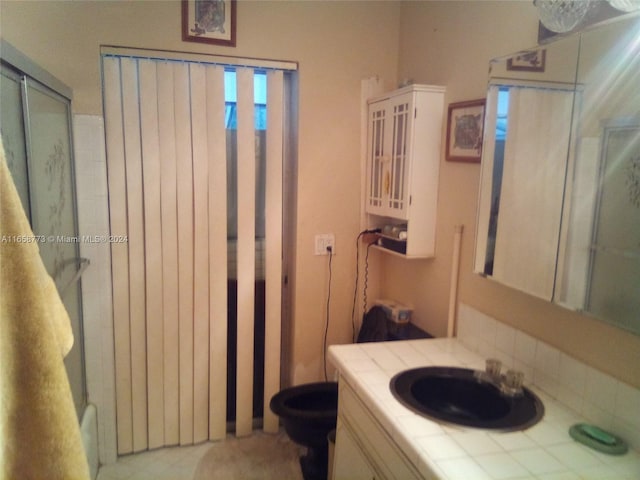 bathroom featuring a shower with shower door and vanity