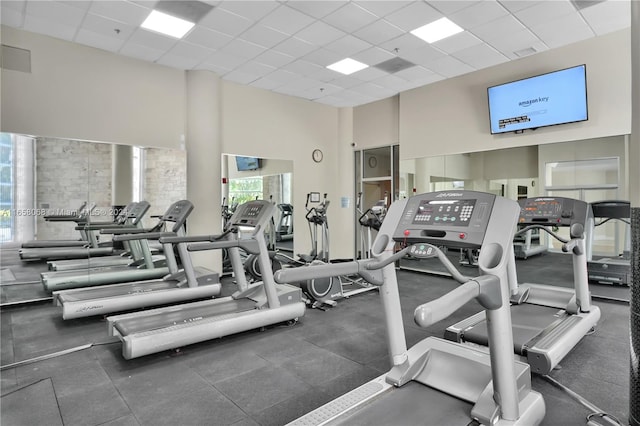 workout area with a towering ceiling and a paneled ceiling