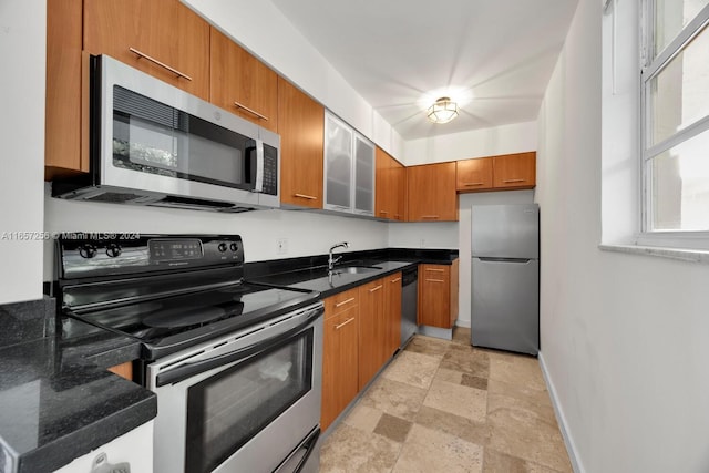 kitchen featuring dark stone countertops, appliances with stainless steel finishes, and sink