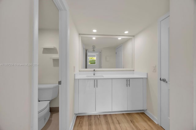 bathroom featuring wood-type flooring, vanity, and toilet