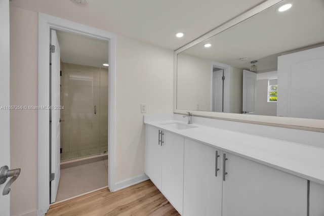 bathroom with walk in shower, vanity, and hardwood / wood-style floors