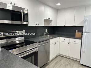 kitchen featuring stainless steel appliances, sink, white cabinetry, and light hardwood / wood-style flooring