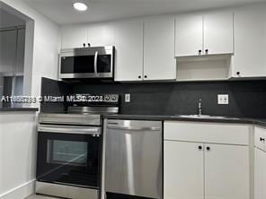 13499 Biscayne Blvd Unit 801, North Miami, FL 33181 - kitchen featuring appliances with stainless steel finishes, a sink, white cabinets, dark countertops, and recessed lighting