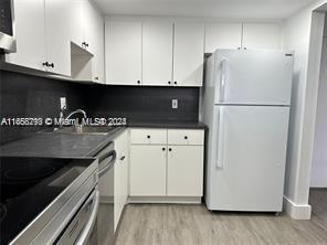 13499 Biscayne Blvd Unit 801, North Miami, FL 33181 - kitchen featuring freestanding refrigerator, light wood-style floors, dark countertops, stove, and white cabinets