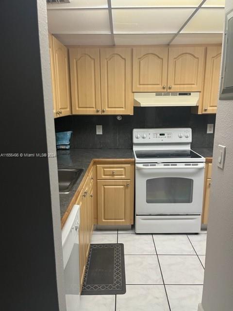 10411 SW 108th Ave Unit 153, Miami, FL 33176 - kitchen with white appliances, light brown cabinets, under cabinet range hood, light tile patterned flooring, and dark countertops
