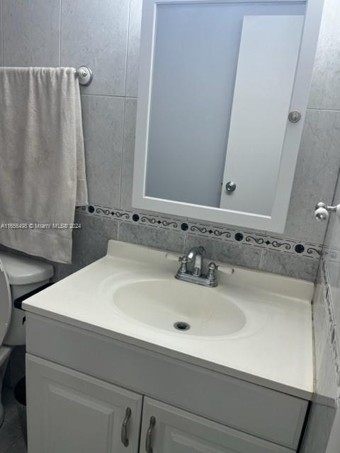 10411 SW 108th Ave Unit 153, Miami, FL 33176 - bathroom featuring vanity, tile walls, and toilet