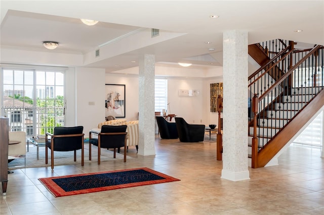 interior space featuring a tray ceiling, decorative columns, light tile patterned floors, and crown molding