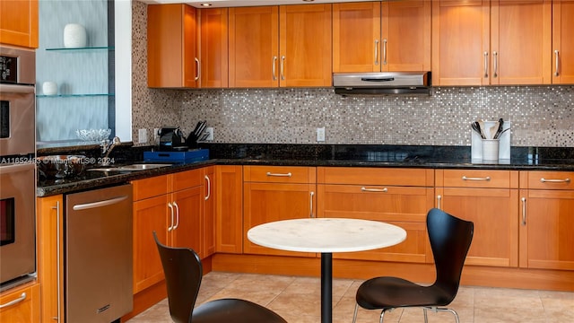 kitchen with appliances with stainless steel finishes, tasteful backsplash, and dark stone counters