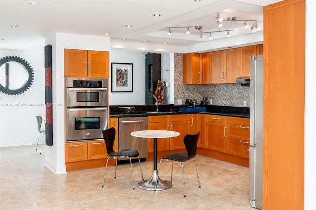 kitchen featuring light tile patterned floors, backsplash, stainless steel appliances, sink, and dark stone counters