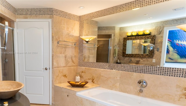 bathroom with tile walls and shower with separate bathtub