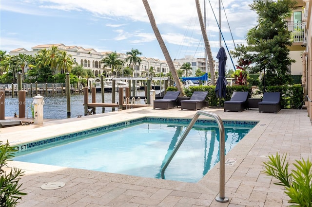 view of pool with a boat dock, a patio, and a water view