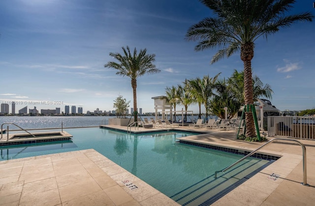 view of pool featuring a water view and a patio