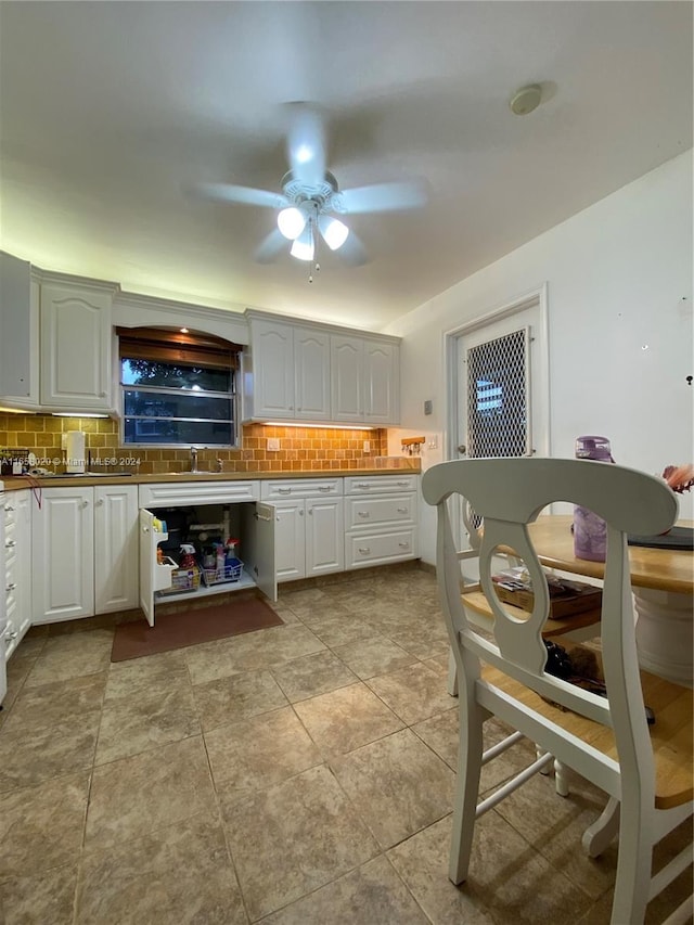 kitchen featuring white cabinets, ceiling fan, decorative backsplash, and sink