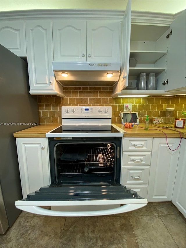 kitchen with wooden counters, electric stove, and white cabinetry