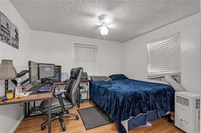 bedroom with a textured ceiling, ceiling fan, and hardwood / wood-style floors