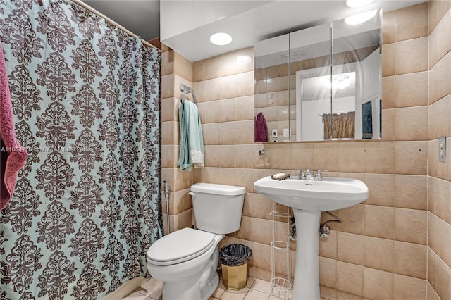 bathroom with tile walls, toilet, curtained shower, and tile patterned flooring