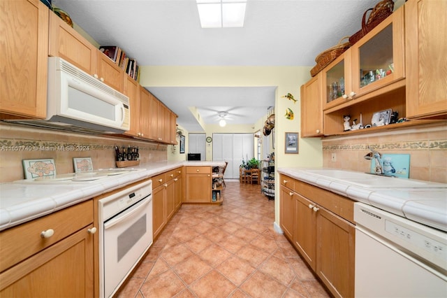 kitchen with white appliances, tasteful backsplash, kitchen peninsula, sink, and ceiling fan