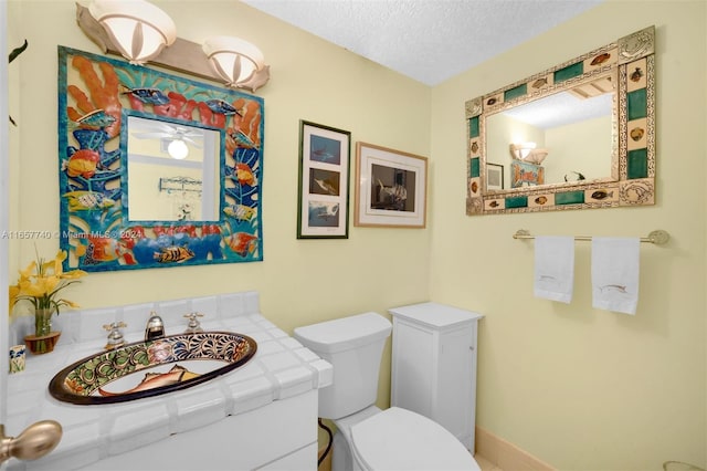 bathroom with a textured ceiling, vanity, and toilet