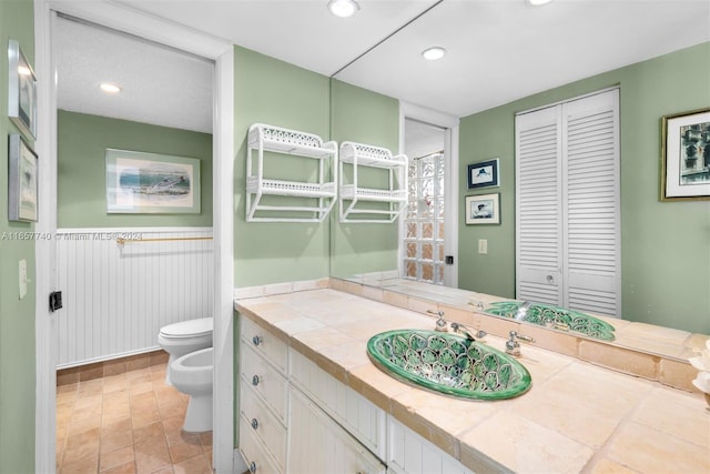 bathroom featuring toilet, a bidet, and vanity