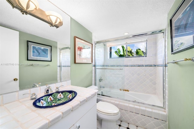 full bathroom with a textured ceiling, vanity, combined bath / shower with glass door, tile patterned flooring, and toilet