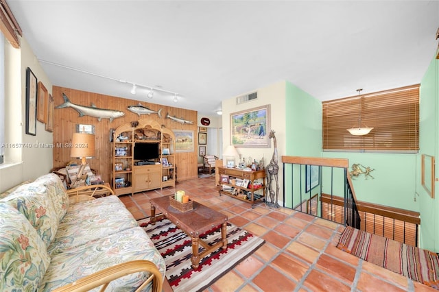 living room featuring wood walls, tile patterned floors, and track lighting