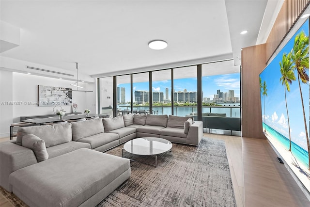 living room with a water view, light hardwood / wood-style flooring, and expansive windows