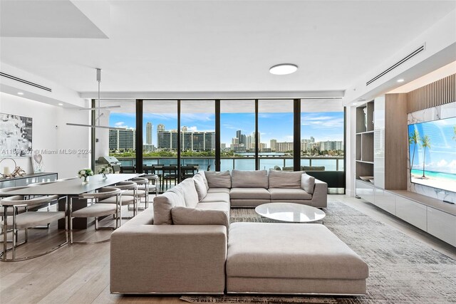 living room featuring floor to ceiling windows, light wood-type flooring, and a water view