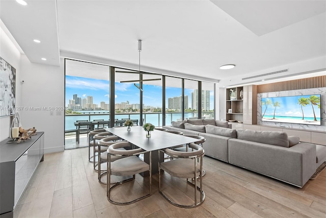 dining area with plenty of natural light, a wall of windows, a water view, and light hardwood / wood-style floors