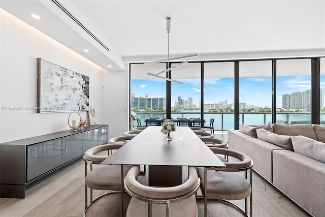 dining area featuring floor to ceiling windows, a water view, and light hardwood / wood-style floors