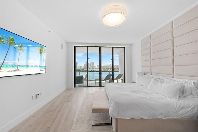 unfurnished bedroom featuring a water view, light hardwood / wood-style floors, and access to outside