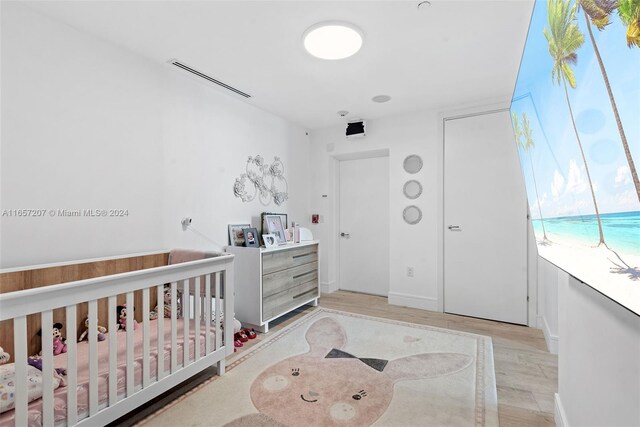 bedroom with a nursery area and light hardwood / wood-style floors