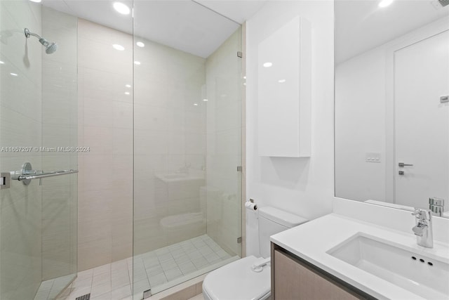 bathroom featuring a shower with shower door, toilet, and vanity