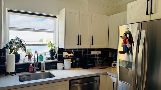 kitchen with backsplash, appliances with stainless steel finishes, crown molding, sink, and white cabinets