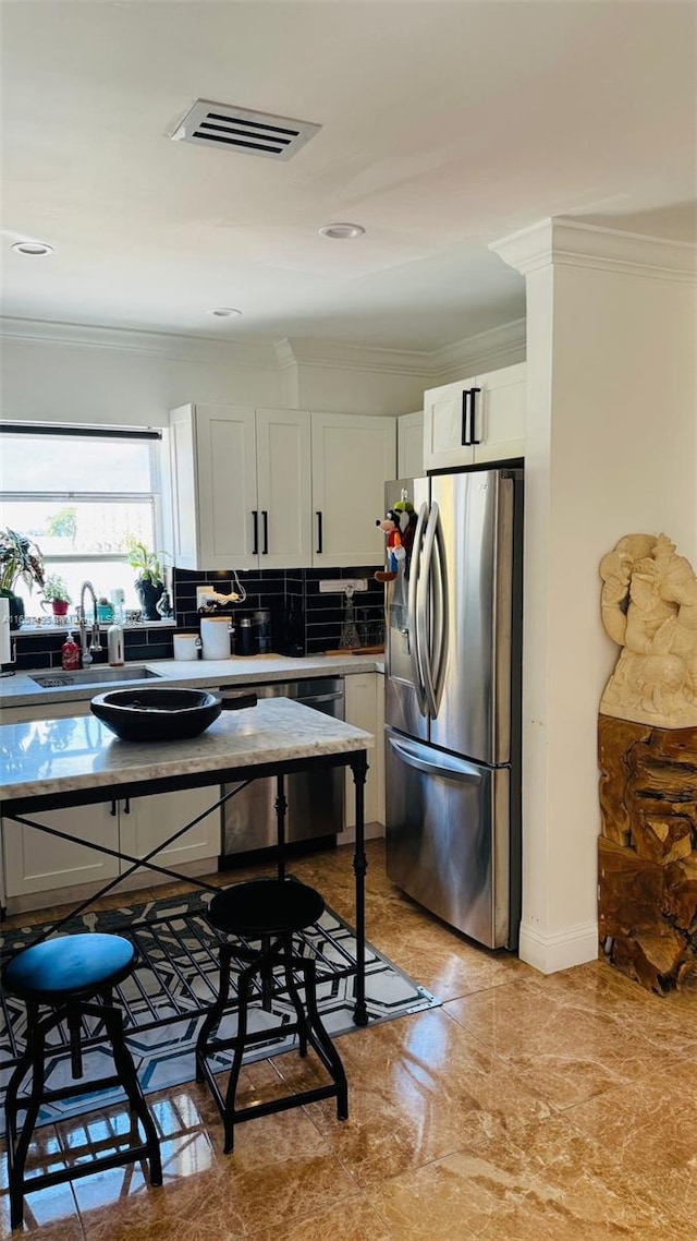 kitchen with sink, appliances with stainless steel finishes, white cabinetry, and tasteful backsplash