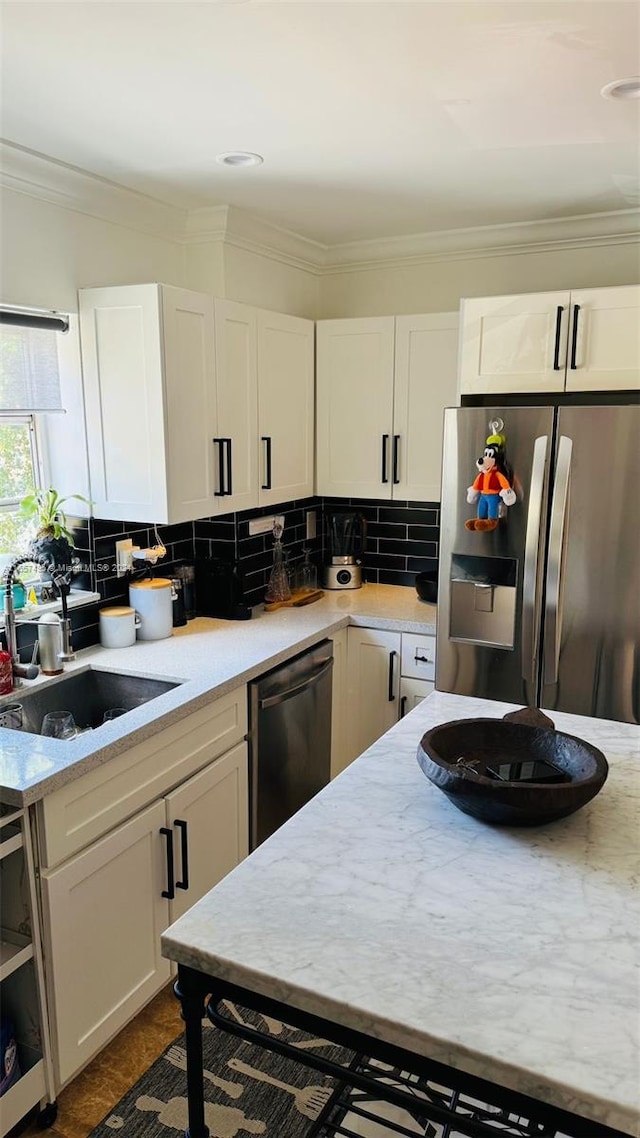 kitchen featuring backsplash, sink, appliances with stainless steel finishes, and white cabinets