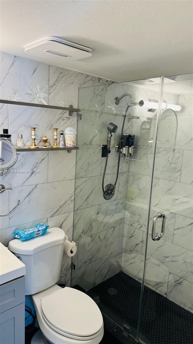 bathroom featuring a textured ceiling, vanity, an enclosed shower, tile walls, and toilet