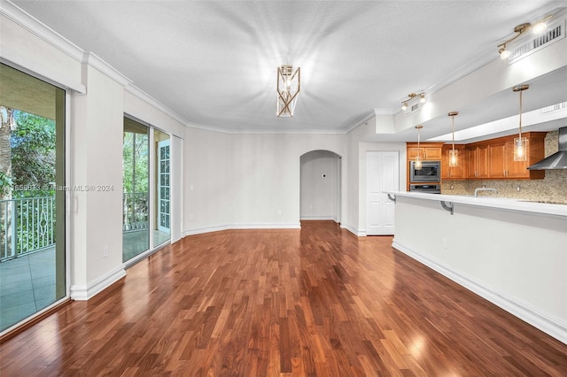 unfurnished living room with hardwood / wood-style floors, sink, a textured ceiling, and ornamental molding